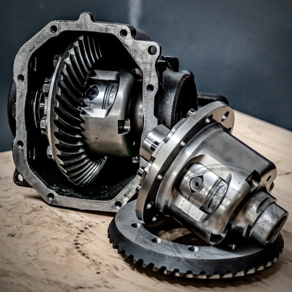 Zwei 55Parts & Westwood Performance Drexler Lamellensperrdifferentiale, eines zusammengebaut und eines teilweise zerlegt, werden auf Holz gezeigt – ideal für jeden, der fast jedes BMW-Modell mit einem mechanischen Sperrdifferential aufrüstet.