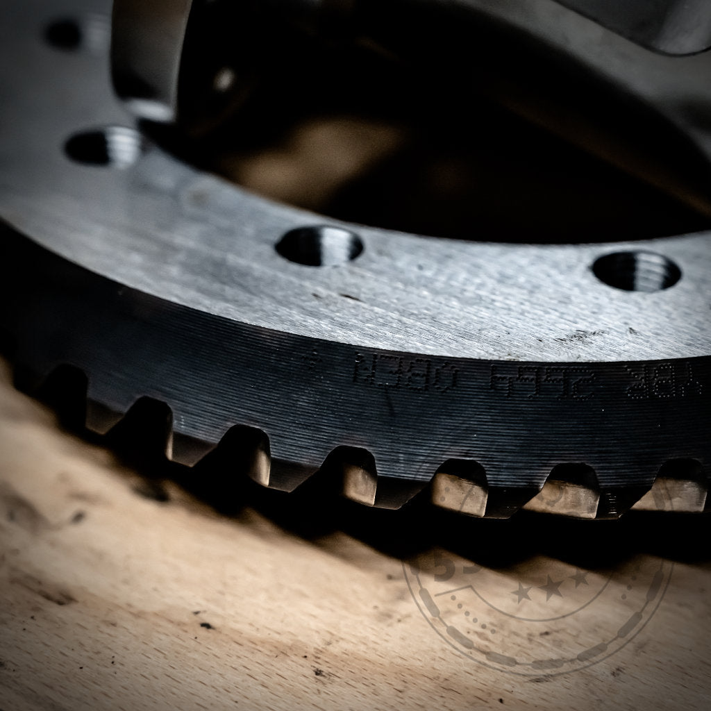 Nahaufnahme eines Metallzahnrads mit scharfen Zähnen auf Holz, das die Präzision des 55Parts Special zeigt: Mechanisches Drexler Lamellensperrdifferential & Westwood Performance, passend für die meisten BMW-Modelle.