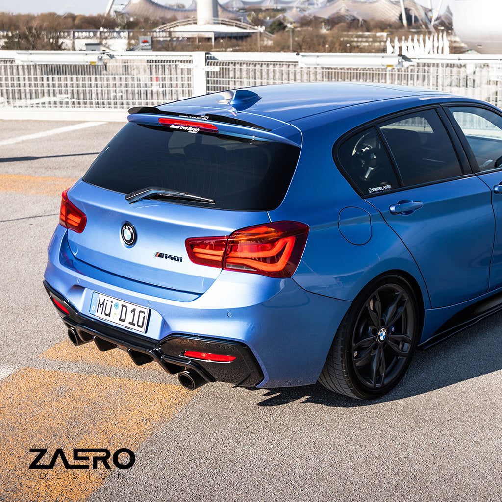 Ein blauer BMW M135i/M140i F2x Fließheck, von hinten links im Außenbereich gesehen, zeigt das ZAERO-Branding und einen eleganten ZAERO Evo-1-Diffusor in glänzendem Schwarz.