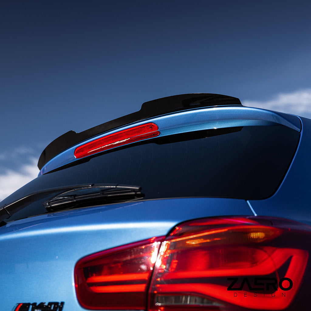 Nahaufnahme eines ZAERO Heckspoilers passend für BMW F2x in Glanz Schwarz auf der Heckscheibe und dem Rücklicht eines blauen Autos, unter blauem Himmel, mit dem ZAERO-Logo in der Ecke.