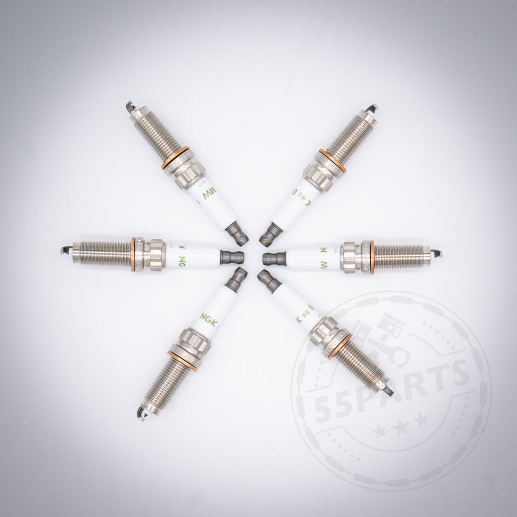 Sechs BMW Zündkerzen-Set 6-Zylinder N20 Flex Fuel Zündkerzen für S55 M2c, M3 und M4 sind kreisförmig auf einer weißen Fläche mit einem schwachen Logo-Wasserzeichen angeordnet.