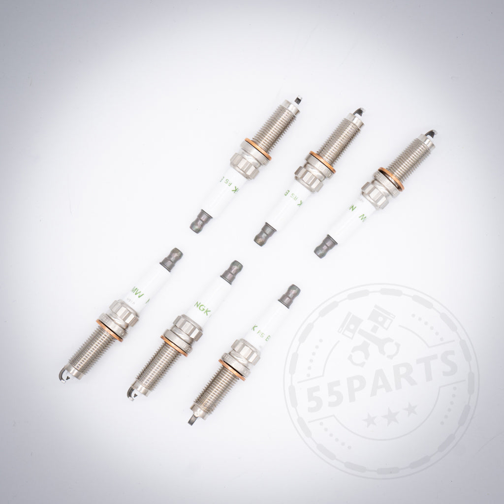 Sechs BMW Zündkerzen-Set 6-Zylinder N20 Flex Fuel Zündkerzen für S55 M2c, M3, M4, diagonal angeordnet auf weißem Hintergrund mit einem schwachen 55Parts-Logo in der Ecke.
