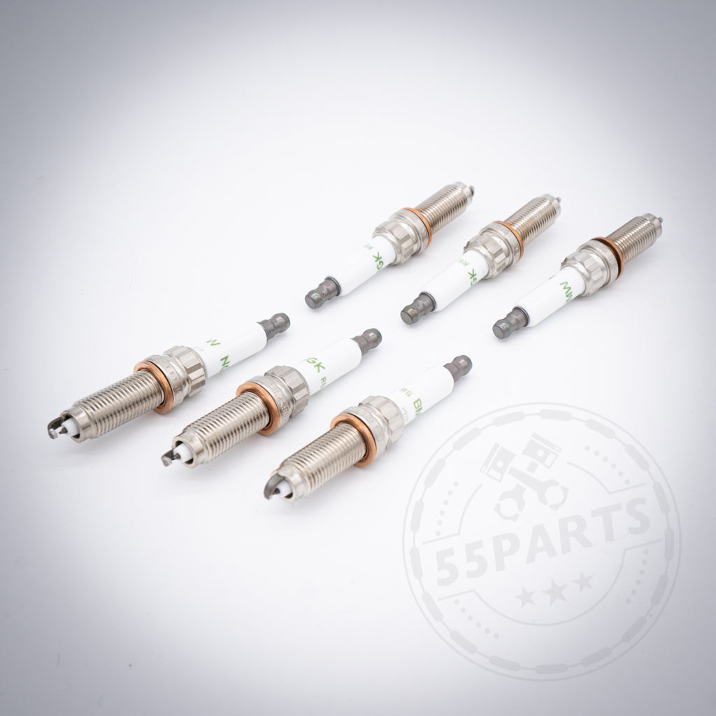 Sechs BMW Zündkerzen-Set 6-Zylinder N20 Flex Fuel-Zündkerzen für S55 M2c, M3 und M4 sind diagonal auf einem weißen Hintergrund mit einem schwachen 55Parts-Logo in der Ecke angeordnet.