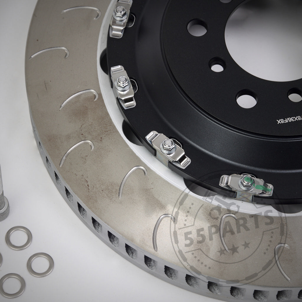 Nahaufnahme des 55Parts-Specials: AP Racing Big Brake Kit – Umrüstkit auf Aftermarket-Reibringe, mit geschlitzter Bremsscheibe, Montagezubehör und Unterlegscheiben auf weißem Hintergrund.