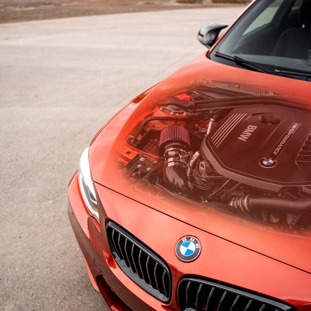 Das Bild zeigt einen BMW, der mit der speziellen offenen Ansaugung ausgestattet ist, die für B58-Motoren in Modellen wie M140i, M240i, 340i und Supra MK5 entwickelt wurde – und hebt die fortschrittliche Technik durch eine digitale Motorüberlagerung hervor.