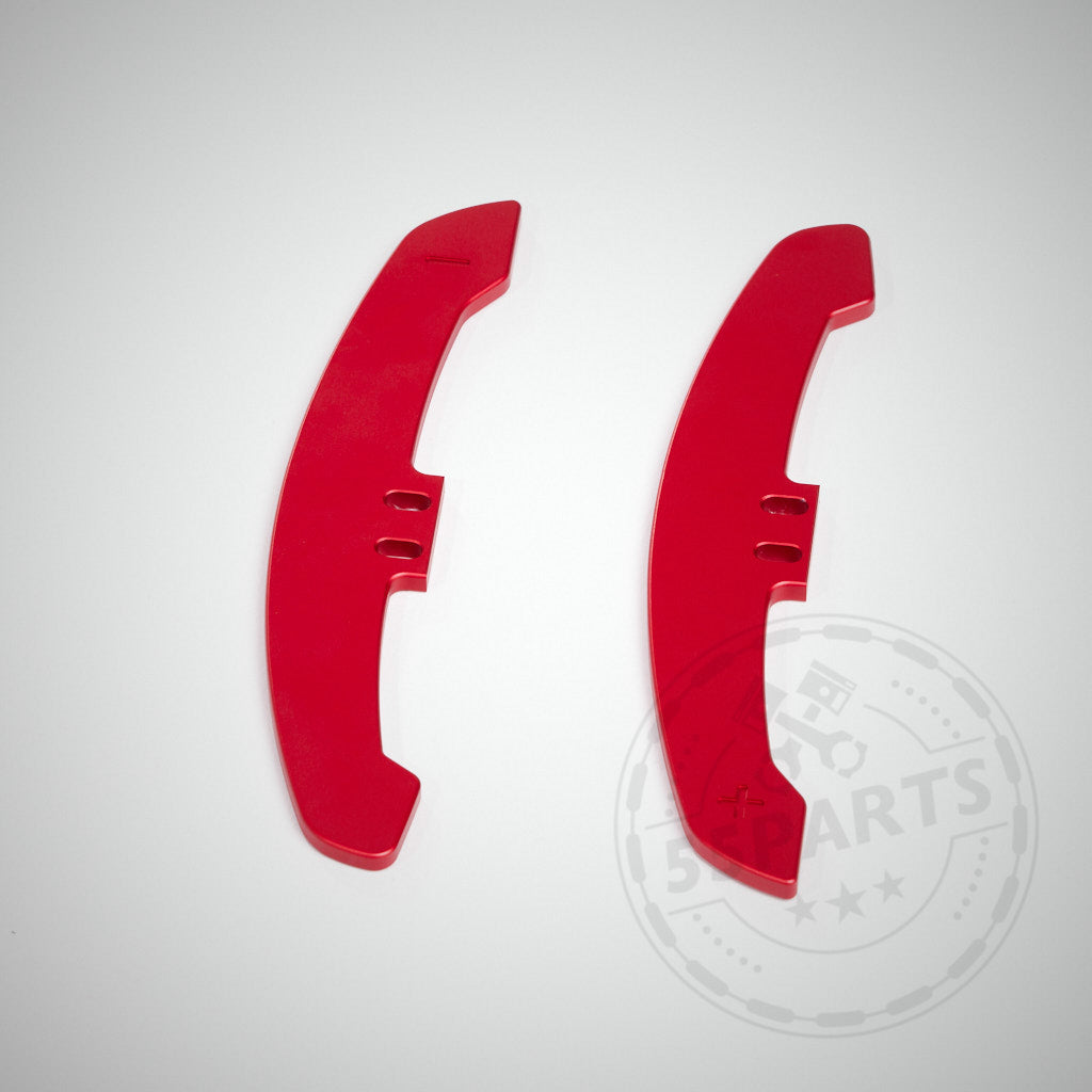 Auf weißem Hintergrund sind zwei rote CNC-gefertigte Aluminium-Schaltwippenverlängerungen Special für magnetische Schalthebel mit Aussparungen und Plus-/Minus-Symbolen abgebildet.