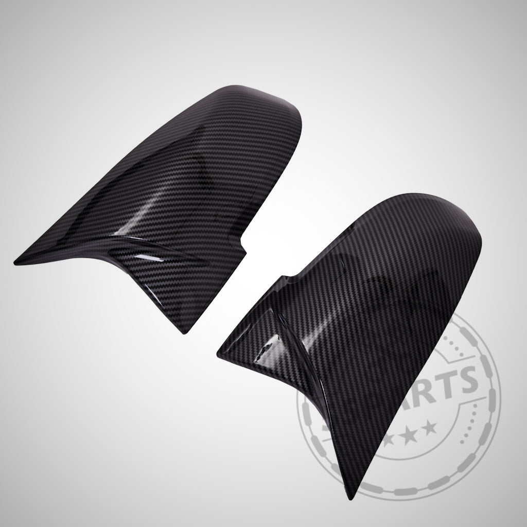Auf hellgrauem Hintergrund sind zwei glänzend schwarze 55Parts Spiegelkappen Design passend für BMW F87 F2x F3x (M2, M135i, M140i, M340i) abgebildet.