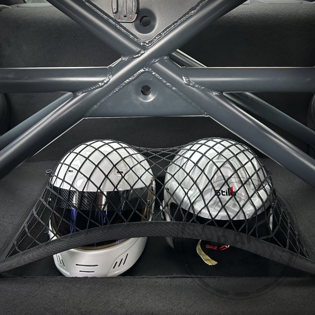 Zwei unter einem Netz gesicherte Helme in einer BMW F-Reihe mit Schalensitzen und dem 55Parts Exclusive Clubsport Innenraum Ausbau mit Helmfach, inklusive sichtbarem Clubsportbügel, passend für 1er, 2er (M2) und 4er (M4) Modelle.