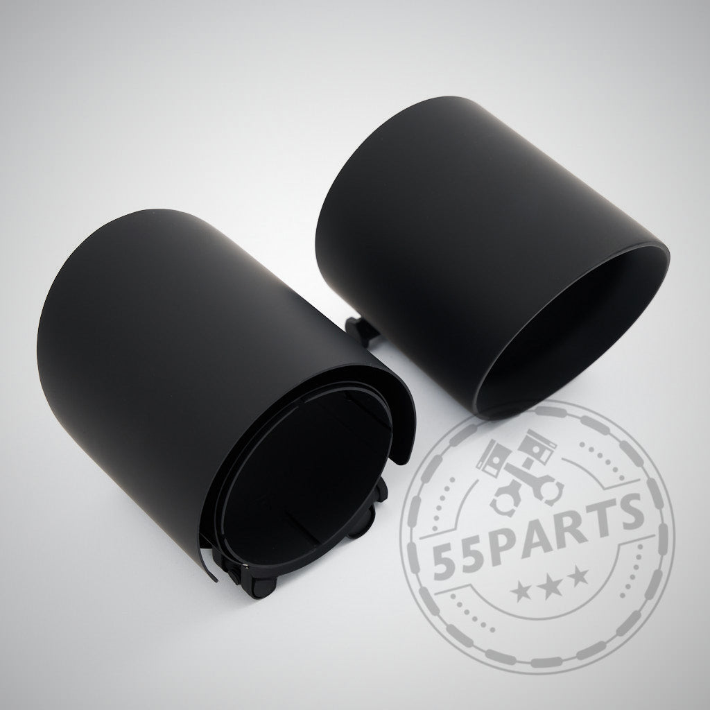 Zwei schwarze zylindrische Kunststoffbecher, einer stehend und einer liegend, auf hellem Untergrund mit einem 55Parts Special: 3" ECE Abgasanlage passend für BMW G8x M2, M3 (Competition, Touring), M4 (Competition) mit S58 Motor.