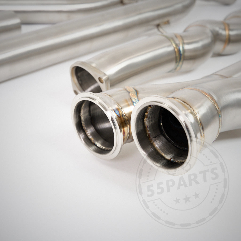 Nahaufnahme von glänzenden Metallauspuffrohren mit sichtbaren Schweißnähten, die das 55Parts Special Equal Length EL Midpipe Resonated mit Schalldämpfern für den S55-Motor des BMW F87 M2 Competition (inkl. CS) zeigen, dargestellt auf einer weißen Oberfläche.