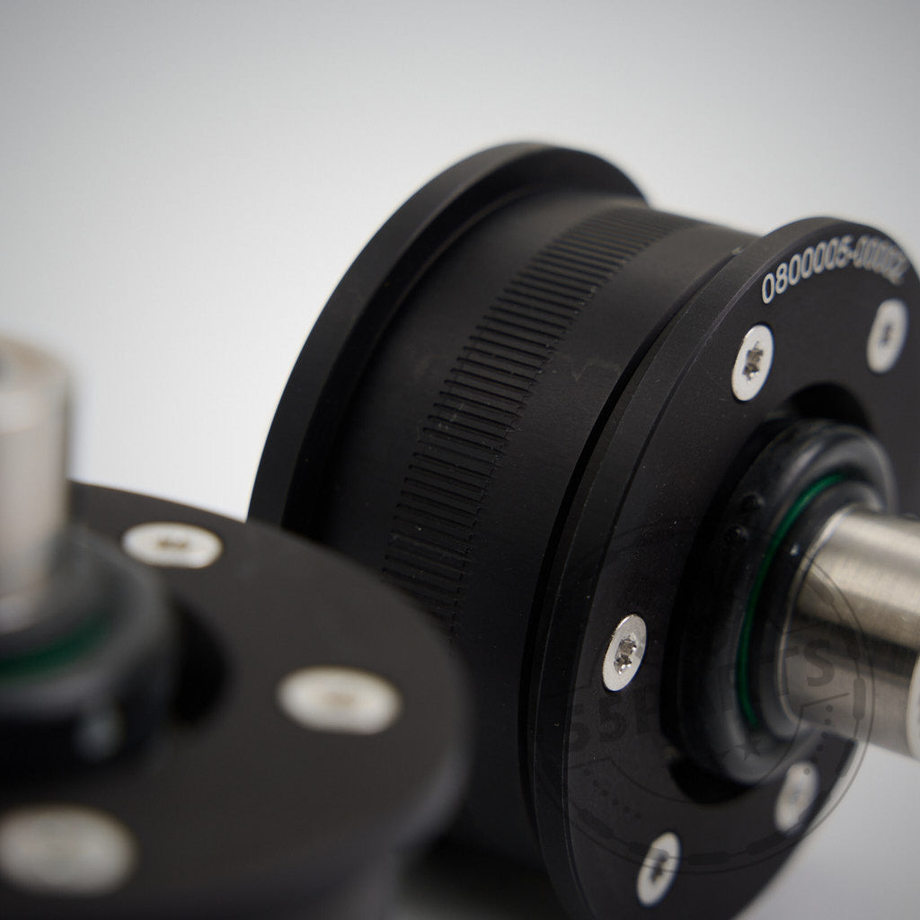 Nahaufnahme zweier schwarzer mechanischer Zahnräder mit Metallschrauben und -wellen, ideal für den Einsatz als NoFlex-Lager: Uniball Lager vordere Zugstrebe, passend für BMW 2er/3er/4er/Z4 G-Serie inkl. xDrive und Toyota Supra GR ALLE MOTOREN.