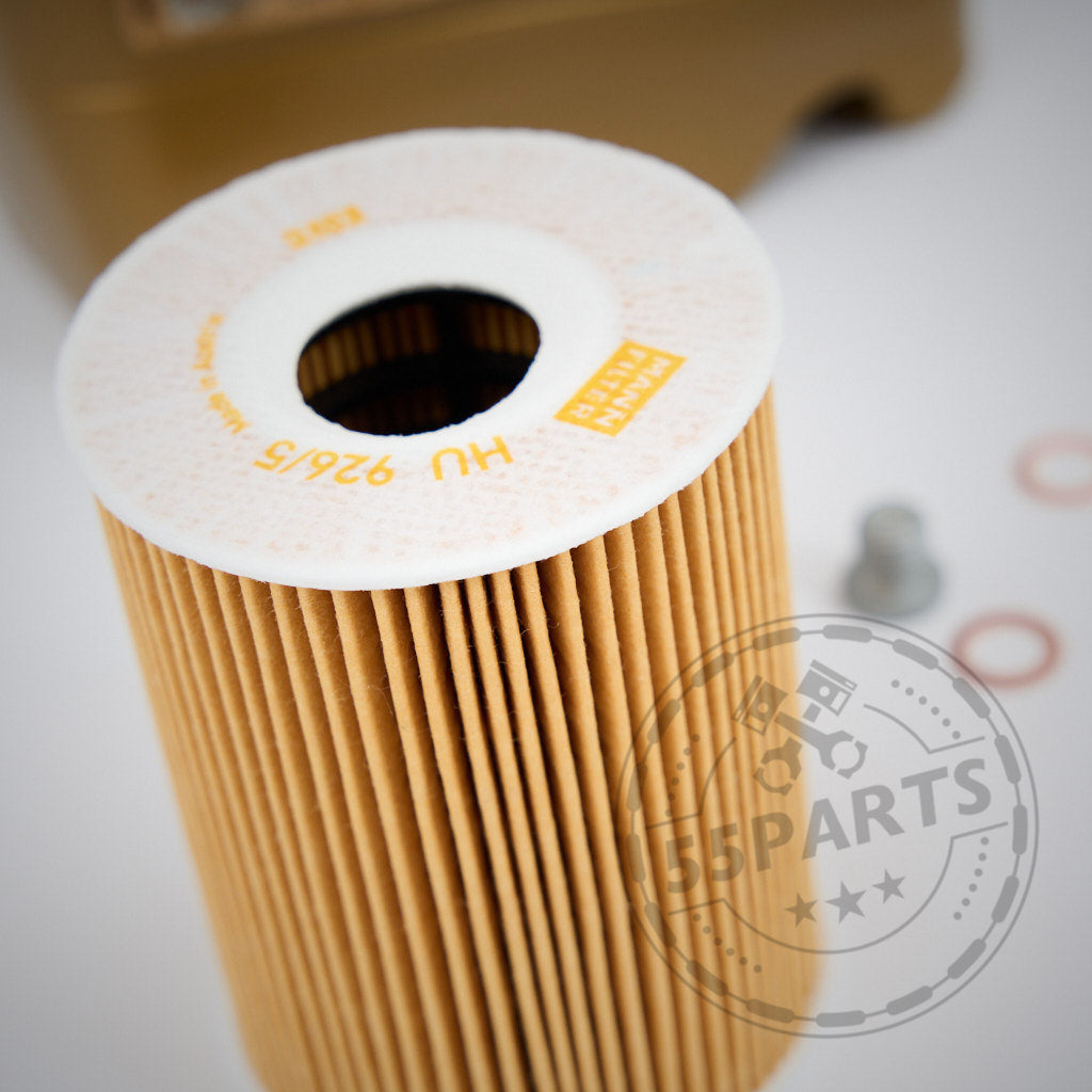 Nahaufnahme eines zylindrisch gefalteten Papierölfilters aus dem 55Parts Ölwechsel Set passend für BMW E9x M3 mit dem S65 Motor, mit kleinen Metallteilen und Unterlegscheiben im Hintergrund.