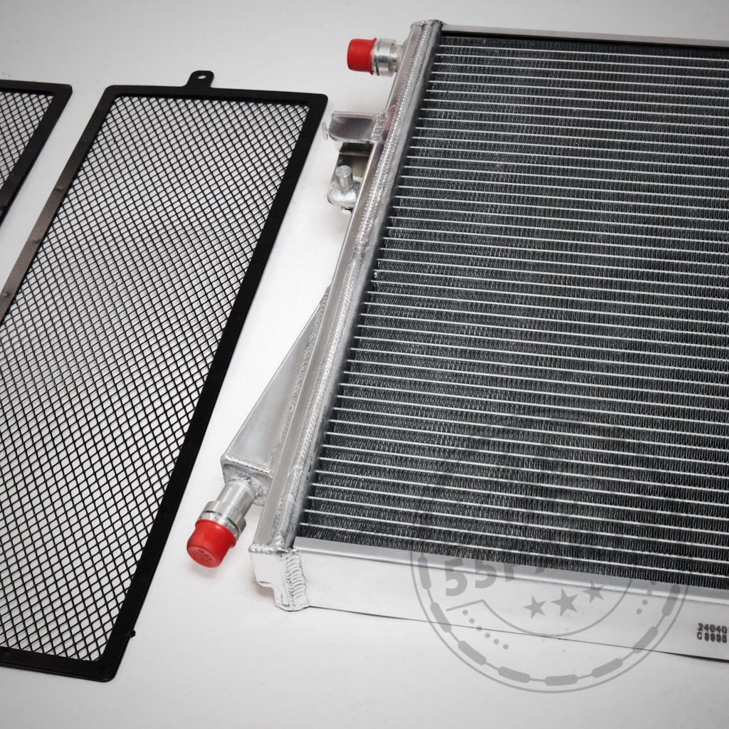 Der 55Parts Upgrade Kühlmittelkühler, Wasserkühler Ladeluftkreislauf passend für BMW G8X M2, M3, M4 mit S58 Motor ist von oben auf einer weißen Fläche mit zwei schwarzen Gitterschutzgittern abgebildet.