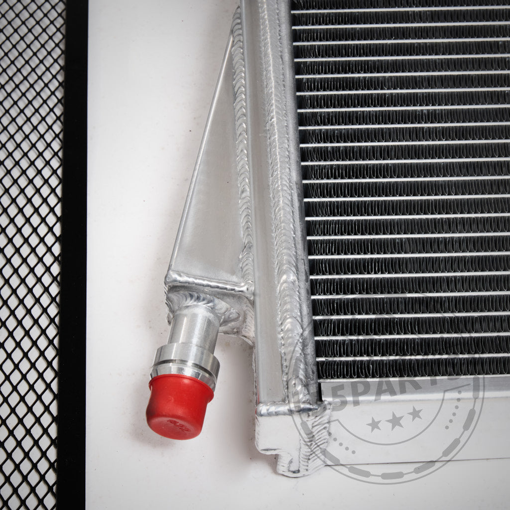 Nahaufnahme des 55Parts Upgrade-Kühlmittelkühlers, ein Wasserkühler-Ladeluftkreislauf mit roter Ventilkappe für den BMW G8X M2-, M3-, M4-S58-Motor, neben einer schwarzen Netzoberfläche dargestellt.