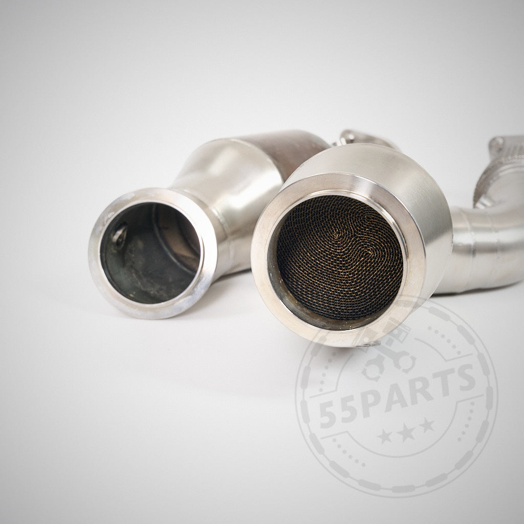 Auf hellem Hintergrund sind zwei High Flow Downpipes mit 200-Zellen-Euro-6-Katalysatoren & MH Pipes passend für BMW G80 M3/G82 M4 S58 abgebildet, die die Ladedruckleistung verbessern sollen.