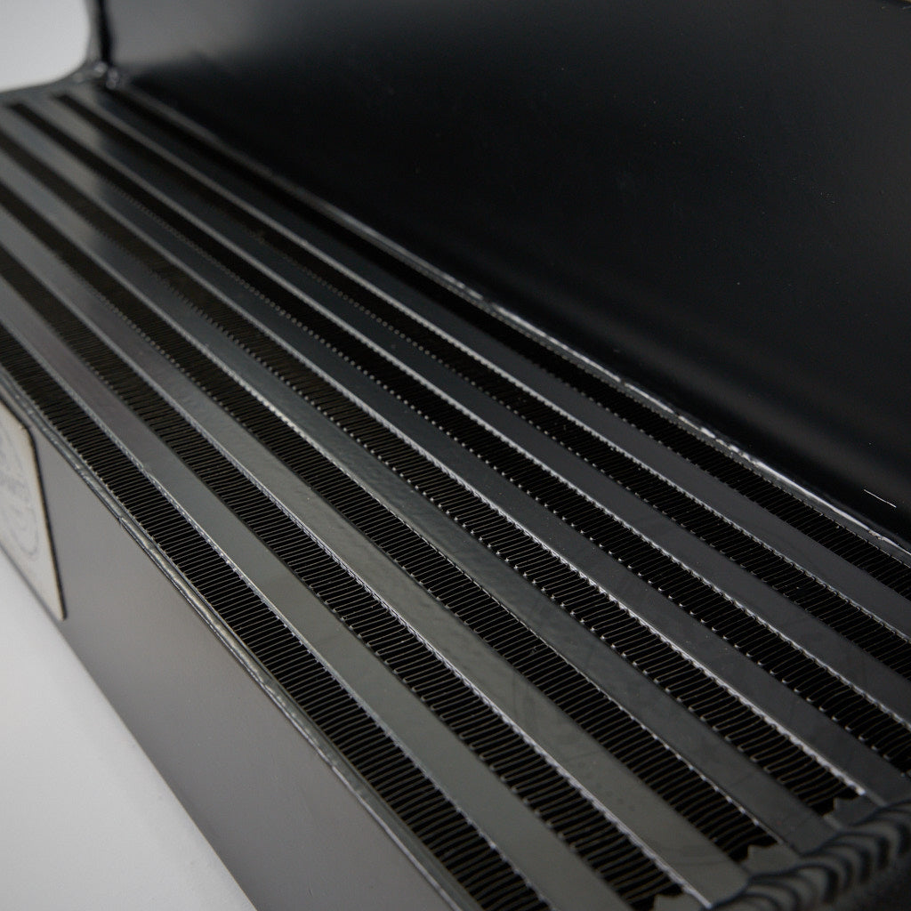 Nahaufnahme der schwarzen Metallbanklatten mit Rillen, aus einem Winkel betrachtet, erinnert an die Präzision des 55Parts-Specials: 7,5-Zoll-Renn-Ladeluftkühlers für den BMW Z4 35I E89 N54-Motor.