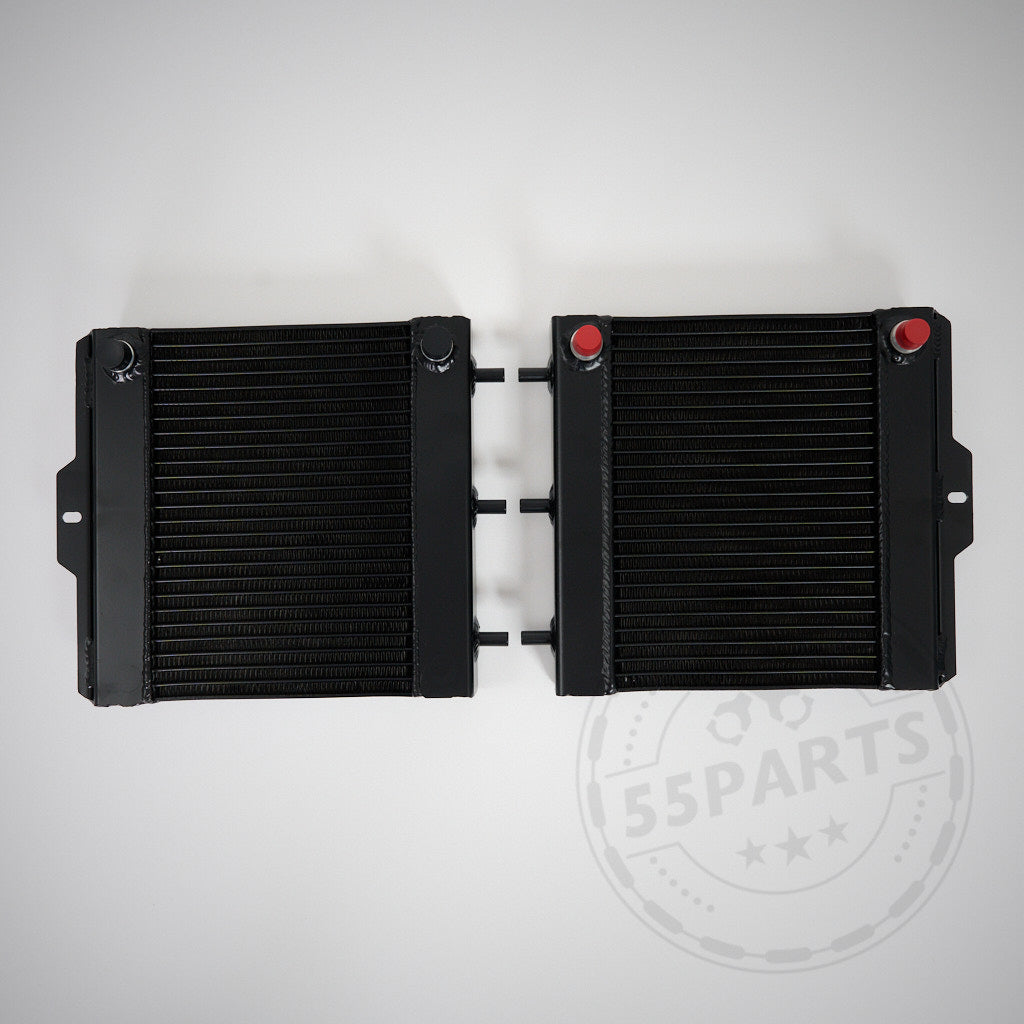 Zwei schwarze 55Parts Aluminium-Upgrade-Kühlmittelkühler, Wasserkühler seitlich passend für BMW M2 Competition, M3, M4 F8x S55, mit roten Kappen, liegen nebeneinander auf hellgrauem Hintergrund.
