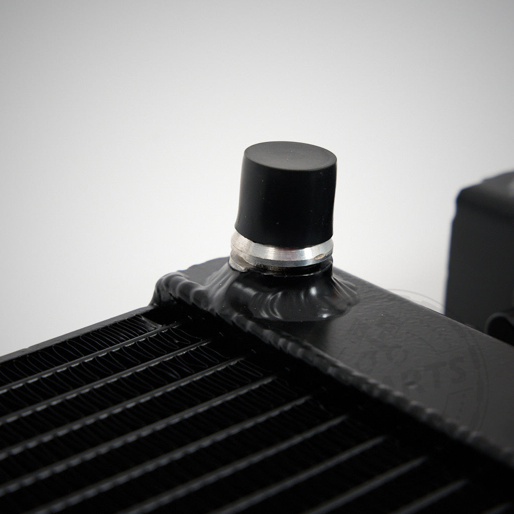 Zwei schwarze 55Parts Aluminium-Upgrade-Kühlmittelkühler, Wasserkühler seitlich passend für BMW M2 Competition, M3, M4 F8x S55, mit roten Kappen, liegen nebeneinander auf hellgrauem Hintergrund.