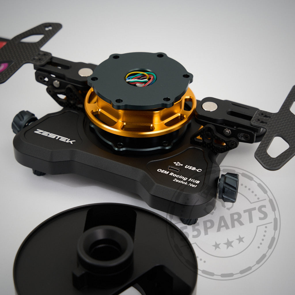 55Parts Exklusiv: Zestek Lenkrad HUB passend für BMW E-, F-, G-Serie und Toyota Yaris/Supra in Schwarz-Gold mit USB-C, freiliegender Verkabelung und Quick Release Mechanismus auf weißem Untergrund neben schwarzem Deckel.