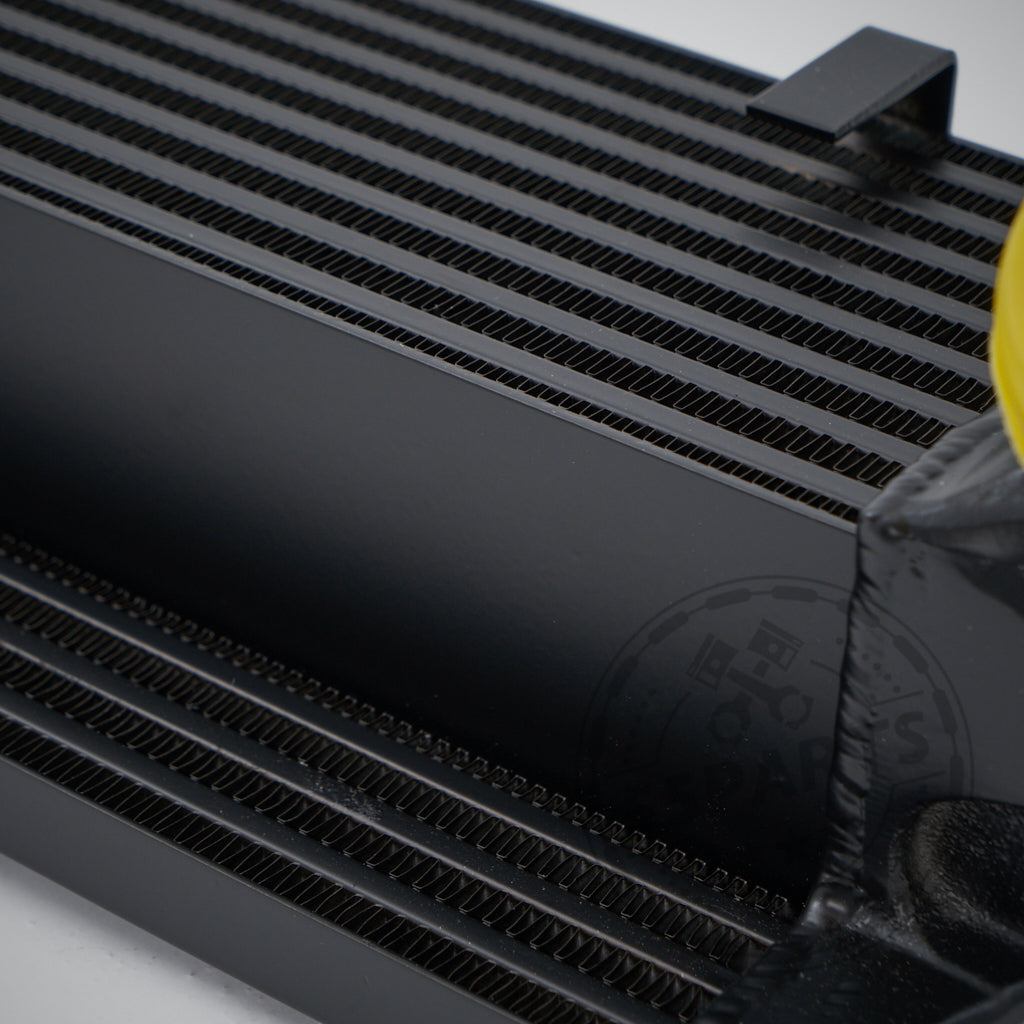 Nahaufnahme des 55Parts Upgrade-Ladeluftkühlers passend für BMW E8x/E9x 118D, 120D, 123D und 320D N47. Mit sichtbaren schwarzen Metalllamellen und einer gelben Kappe – perfekt für Tuning-Builds oder FBO-Setups, die nach hochwertigen Performance-Teilen suchen.