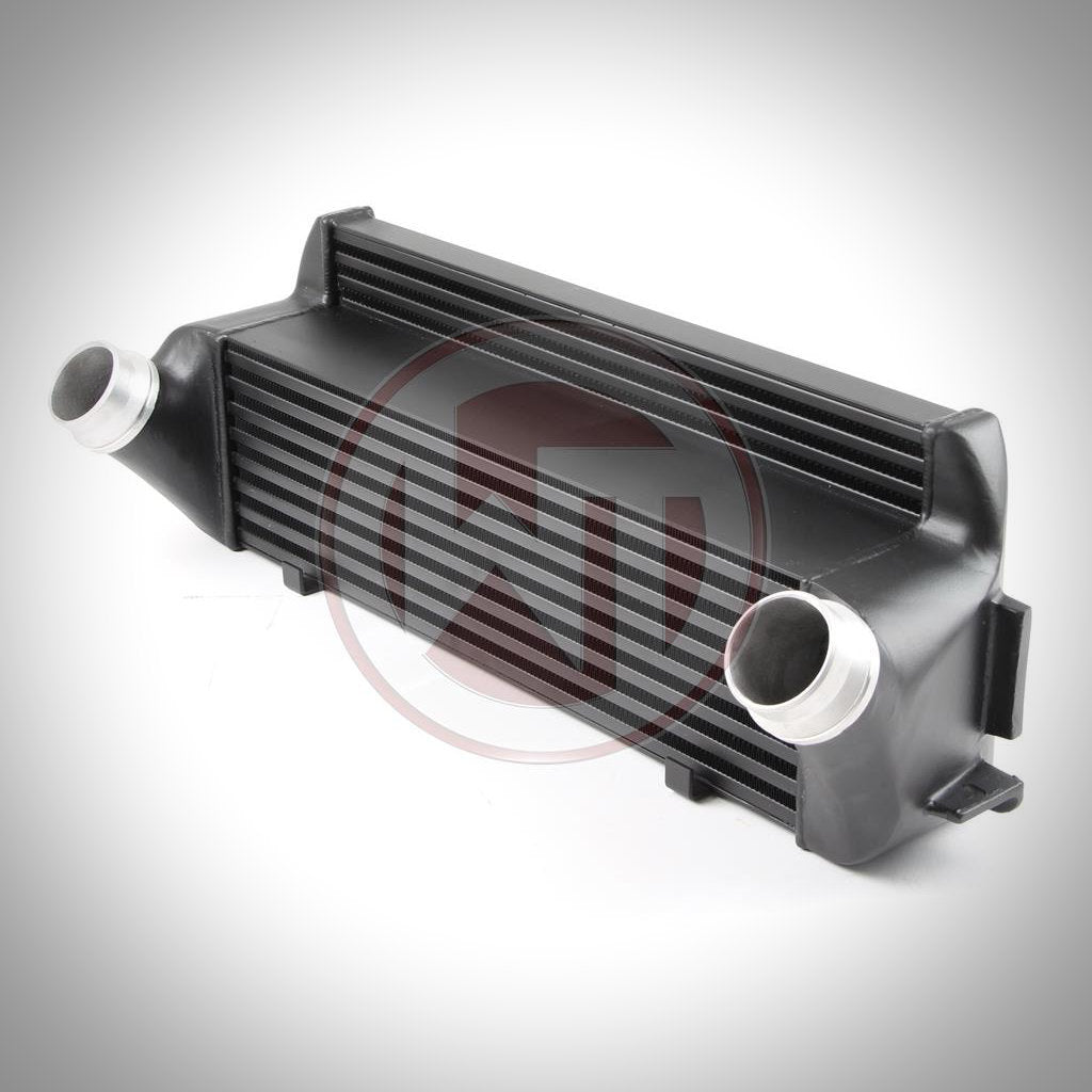 Der Wagner Tuning Evo 1 Competition Ladeluftkühler passend für BMW F2x, F3x in Schwarz, mit Aluminium Einlass- und Auslassrohren, ist auf weißem Hintergrund abgebildet.