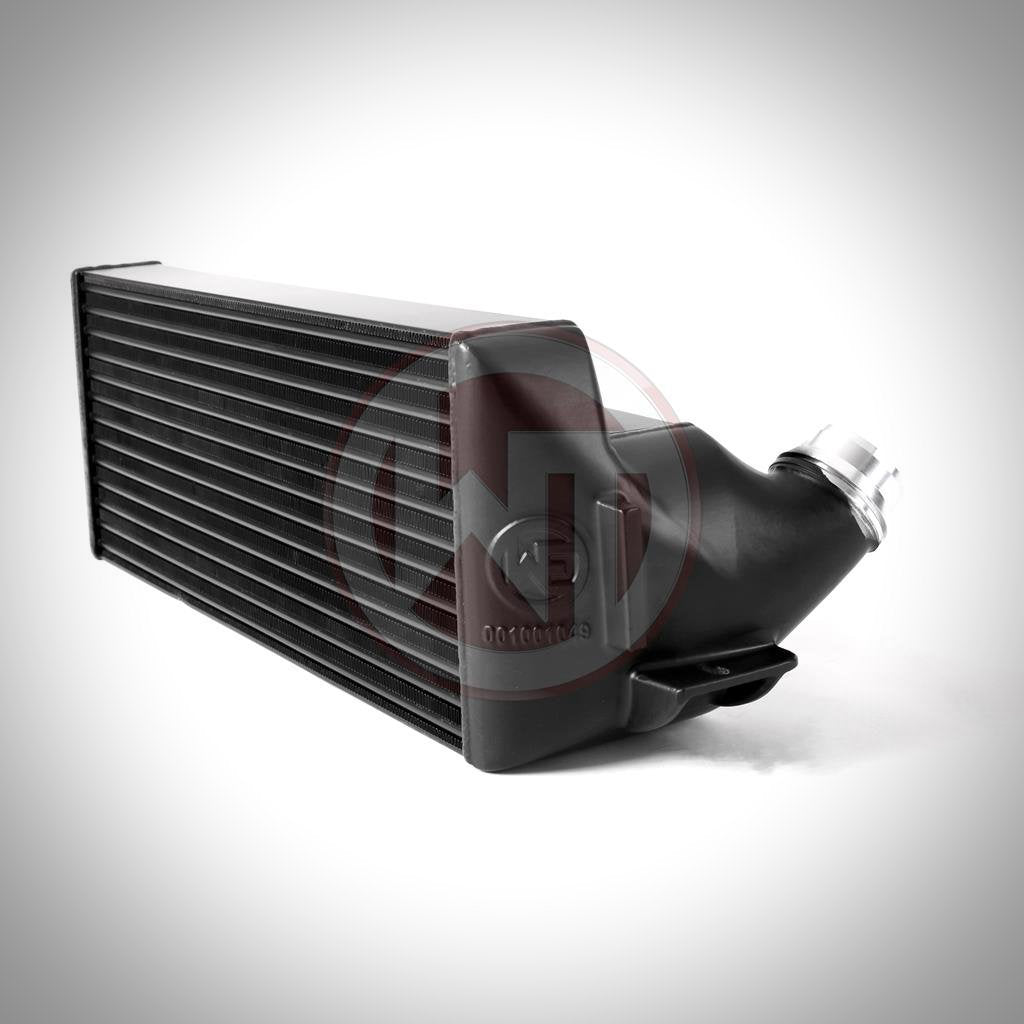 Schwarzer Wagner Tuning Evo 2 Competition Ladeluftkühler passend für BMW F2x, F3x mit abgewinkeltem Endtank und Hochleistungsnetz, dargestellt auf weißem Hintergrund mit Schatten.