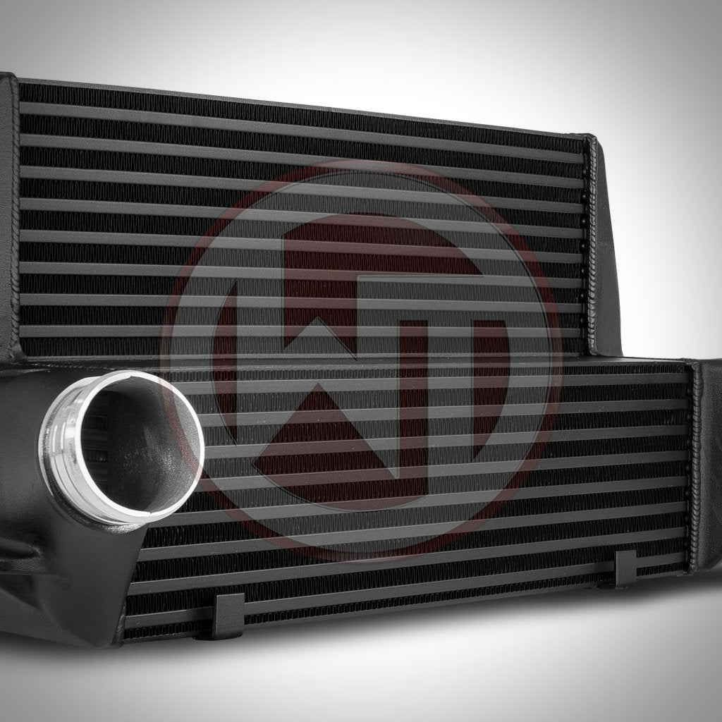 Nahaufnahme des Wagner Tuning Evo 3 Ladeluftkühlers passend für BMW 135i, 1er M Coupé und 335i(x) N54/N55 E-Serie, mit schwarzem Ladeluftkühler und silbernem Ansaugrohr vor weißem Hintergrund.