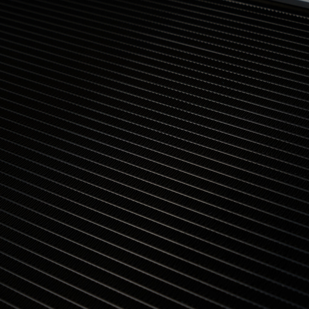 Nahaufnahme der diagonalen, gleichmäßig verteilten schwarzen Metalllamellen vom 55Parts Aluminium-Upgrade-Kühlmittelkühler, Wasserkühler, Ladeluftkreislauf passend für BMW M2 Competition, M3, M4 S55.