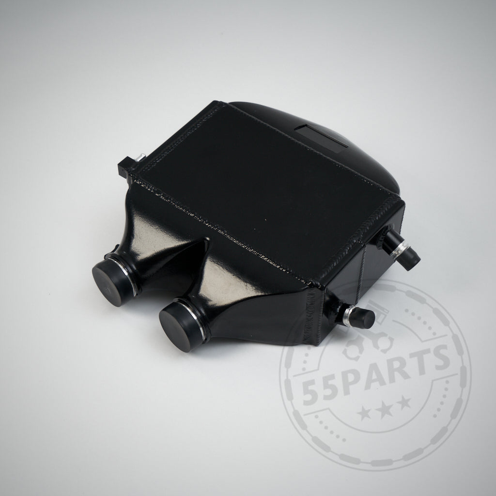 Der Aluminium-Upgrade-Ladeluftkühler passend für BMW M2 Competition, M3 und M4 S55 verfügt über ein schwarzes Metall-Finish mit zwei runden Anschlüssen und Armaturen, die sich vor einem hellen Hintergrund abheben.