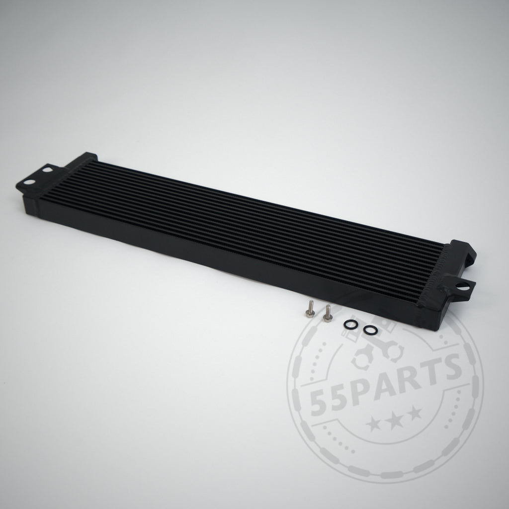Schwarzer rechteckiger Upgrade-Ölkühler mit Befestigungslöchern, Schrauben und Unterlegscheiben auf hellgrauem Hintergrund, passend für BMW M2 Competition, M3 und M4 S55.