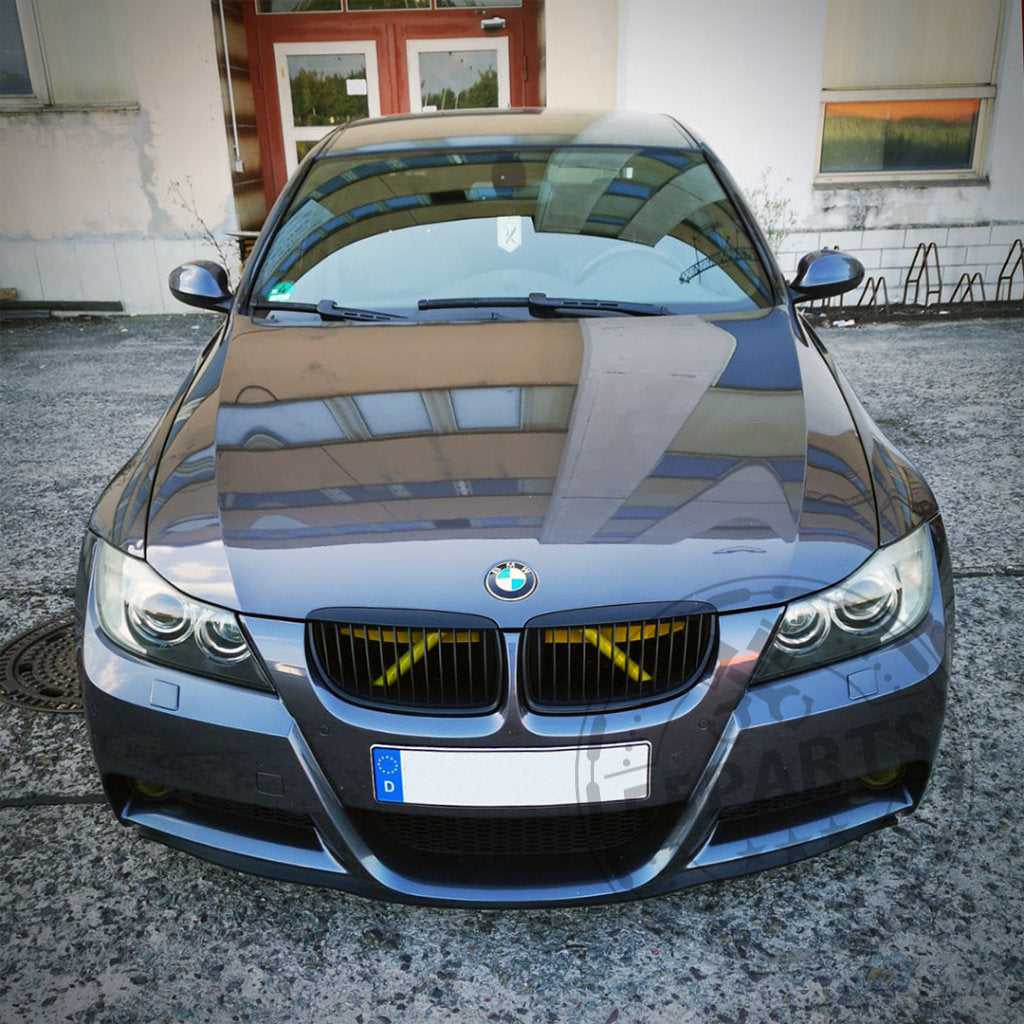 Ein grauer BMW 3er mit einem Bannik Engineering Airscoop (55Parts Exclusive) ist vor einem Gebäude geparkt, von vorne mit Reflexionen auf der Motorhaube betrachtet.