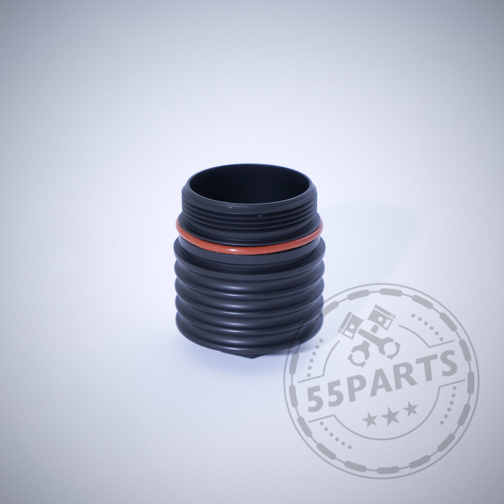 Schwarzes gewelltes zylindrisches Autoteil mit orangefarbenem Ring auf hellem Hintergrund. Features 55Parts Exclusive: Aluminium-Ölfilterkappe mit Sechskant, passend für BMW N20, N57, N52, N53, N54, N55, S55, B46, B48, B57 & B58. Wasserzeichen vorhanden.