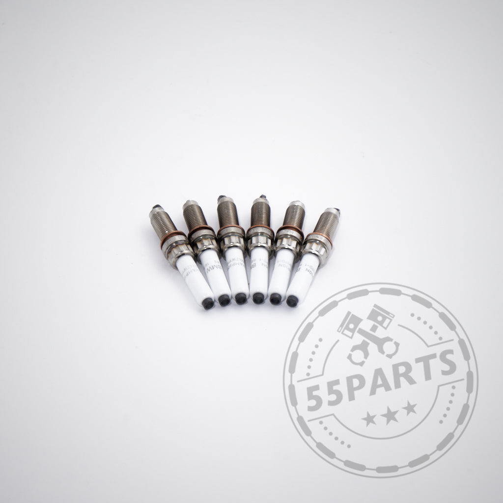 Sechs BMW Zündkerzen für 6-Zylinder-Modelle wie M240i, M340i, M440i, G8x M2/M3/M4, X3M und A90 Supra B58 werden in einer Reihe auf einer weißen Fläche mit dem 55Parts-Logo-Wasserzeichen in der unteren rechten Ecke angezeigt.