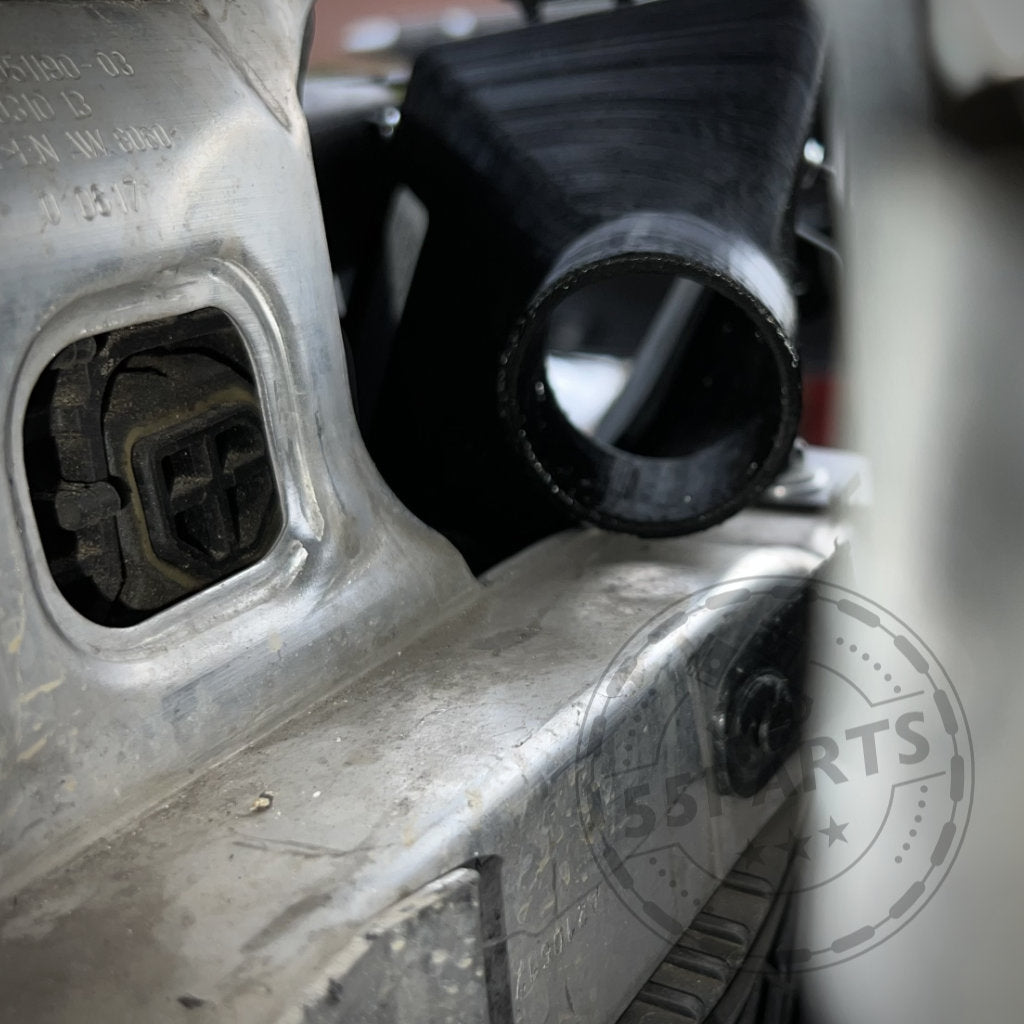 Nahaufnahme eines Autoteils neben einer schwarzen 3D-gedruckten Komponente mit dem teilweise sichtbaren 55Parts-Logo. Ideal für Fans des 55Parts-Exklusivangebots: Bremsbelüftungsset passend für BMW 2er F22 mit M-Paket (M235i, M240i), die eine bessere Performance auf der Rennstrecke anstreben.