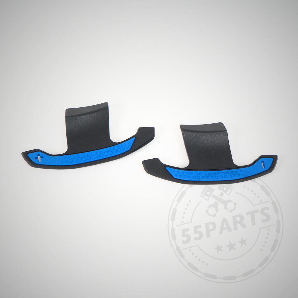 Zwei schwarze 55Parts Carbon Schaltwippen passend für BMW 1/235 und 40i, 3/435 und 40i, M2, M3 und M4 F- & G-Serie mit blauen Akzenten werden auf einem hellen Hintergrund mit dem 55Parts-Wasserzeichen angezeigt.