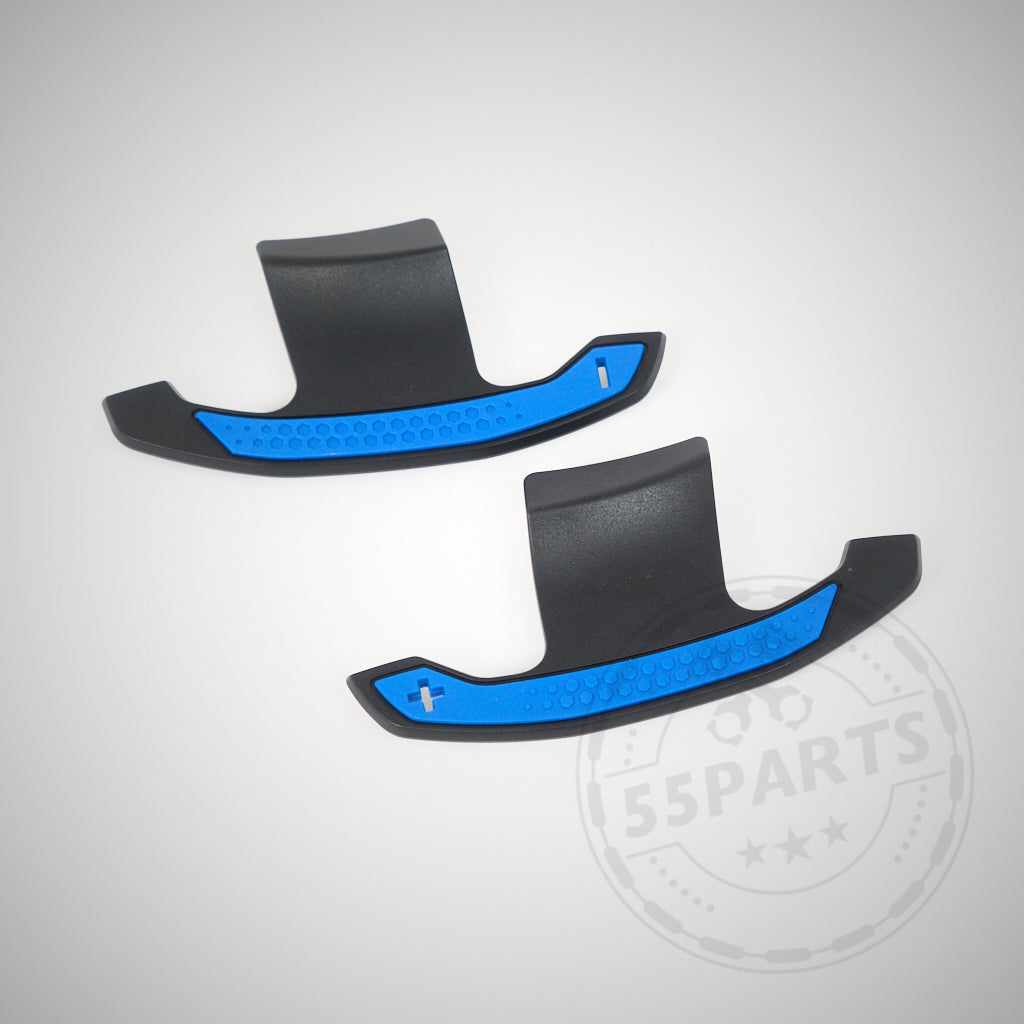 Zwei schwarz-blaue 55Parts Carbon Schaltwippen mit Plus- und Minus-Symbolen, entworfen passend für BMW 1/235 & 40i, 3/435 & 40i, M2, M3 & M4 F- und G-Serie, abgebildet auf hellem Hintergrund.