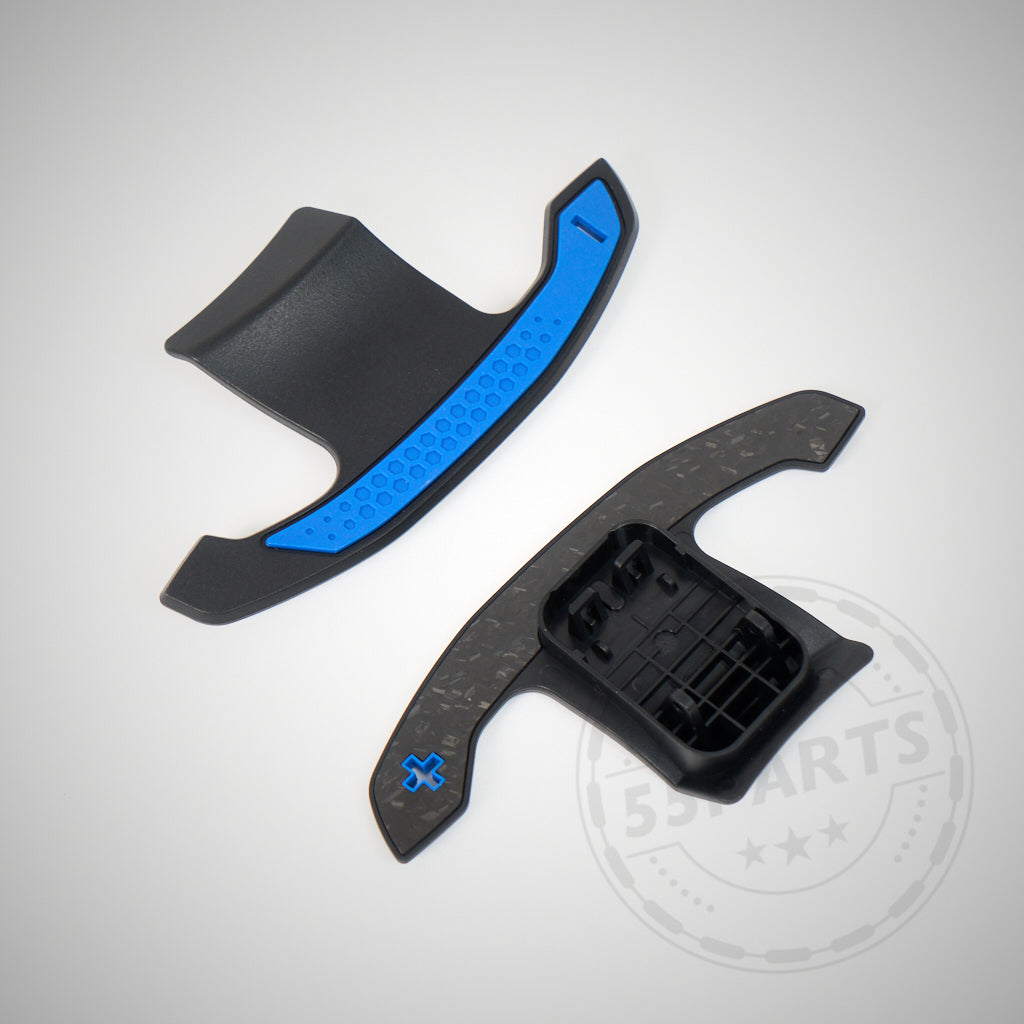 Zwei schwarze Carbon-Schaltwippen, entworfen für die F- und G-Serie von BMW 1/2/3/4 (35 & 40i), M2, M3 & M4, abgebildet mit blauen Akzenten auf hellgrauem Hintergrund.