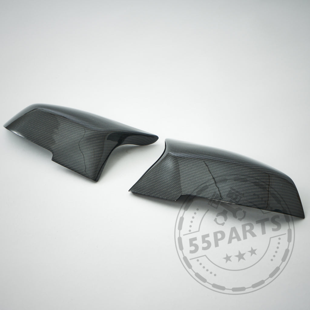 Zwei schwarze 55Parts Spiegelkappen Design-Spiegelabdeckungen passend für BMW F87 F2x F3x M2 M135i M140i M340i werden auf einem hellgrauen Hintergrund mit dem 55Parts-Wasserzeichen angezeigt.