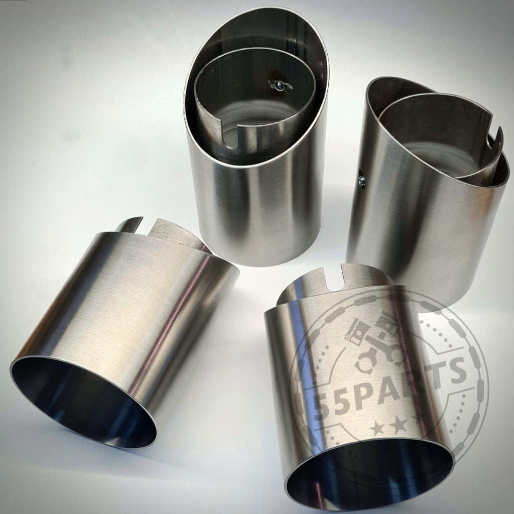 Vier 55Parts Spezial-Endrohrblenden passend für BMW M2(c), M3, M4 F8x mit abgeschrägten Edelstahlkanten liegen auf weißer Fläche mit dezentem Logo-Wasserzeichen.