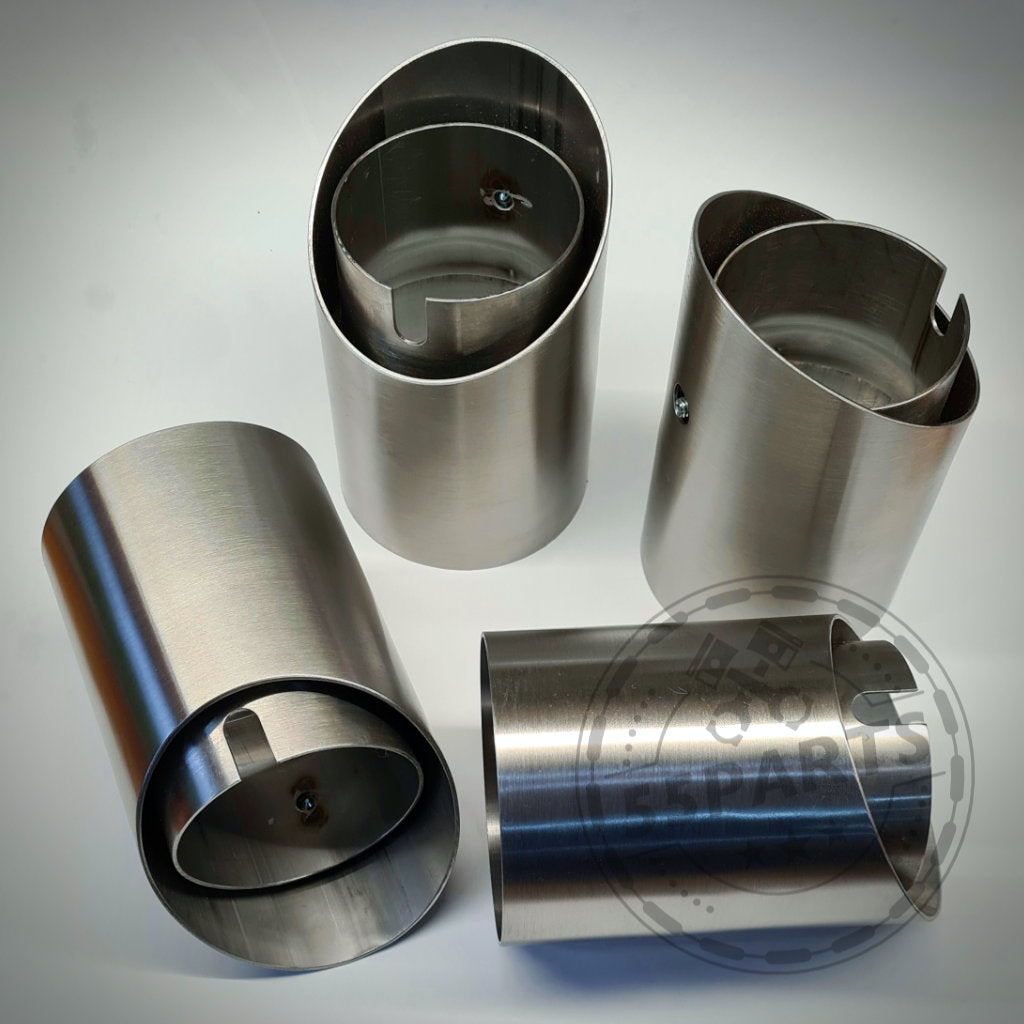 Vier 55Parts Spezial-Endrohrblenden passend für BMW M2(c), M3 und M4 F8x aus Edelstahl mit geschlitztem zylindrischem Design werden auf einer hellen Oberfläche präsentiert.