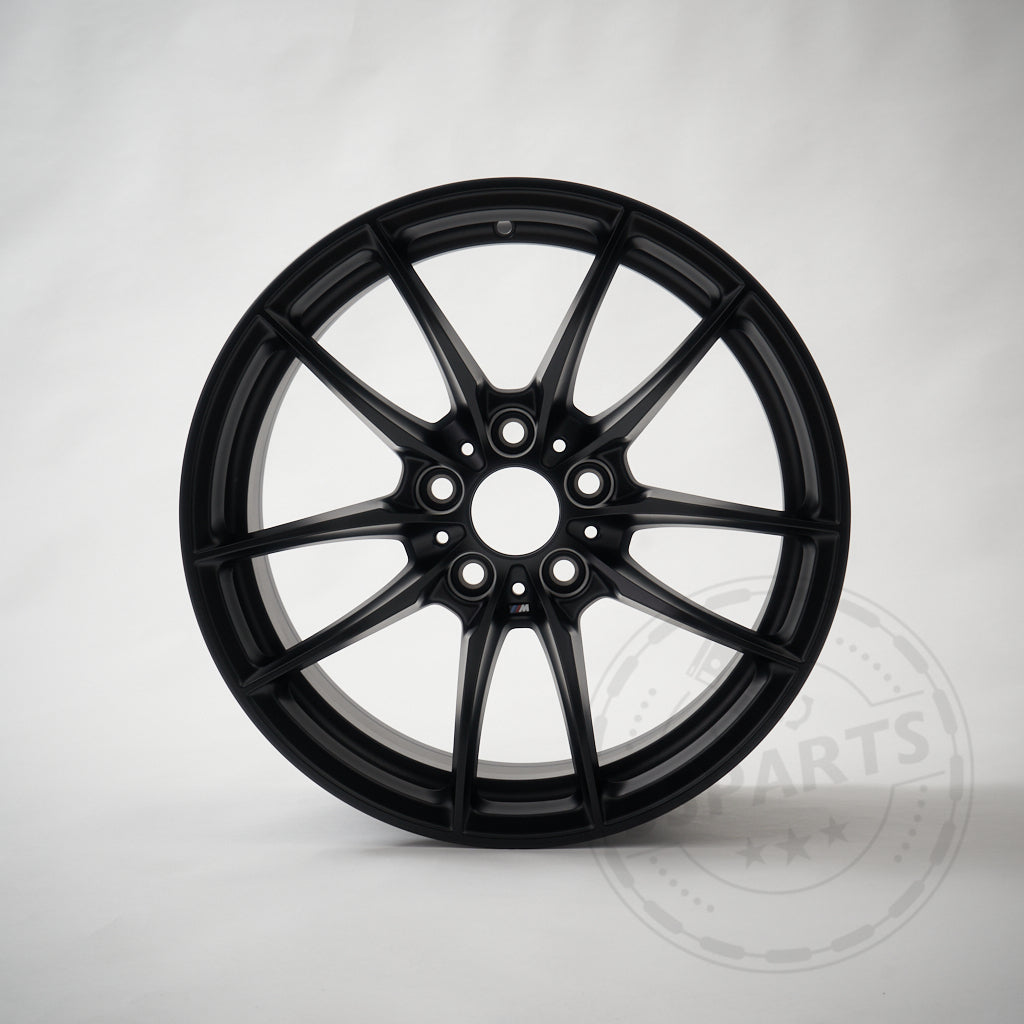 Die Leichtmetallfelge BMW Motorsport M2 CS Racing Felge 10,5x18 ET46 5x120 in Mattschwarz mit 10-Mehrspeichen-Design präsentiert sich auf schlichtem, hellem Untergrund.