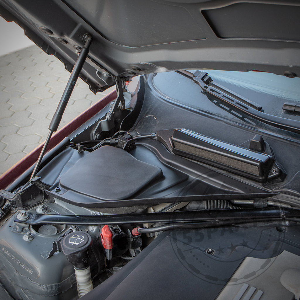 Offene Motorhaube gibt den Blick auf den BMW-Motorraum frei, mit dem Bannik Engineering Mikrofiltergehäuse-Unterteil (für bessere Wärmeabfuhr), kompatibel mit E8x und E9x 1er und 3er, plus Wischerflüssigkeitsdeckel und Scheibenwischermechanismus.