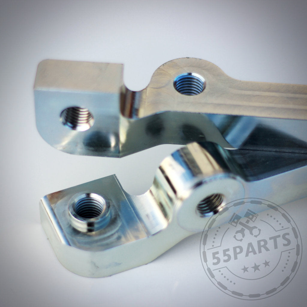 Nahaufnahme von zwei bearbeiteten 55Parts-Metalladaptern passend für BMW 1er E8x – 6-Kolben-Bremssatteladapter für M3 E46 CSL Scheibe, ideal zur Verbesserung der Rennstreckenleistung.
