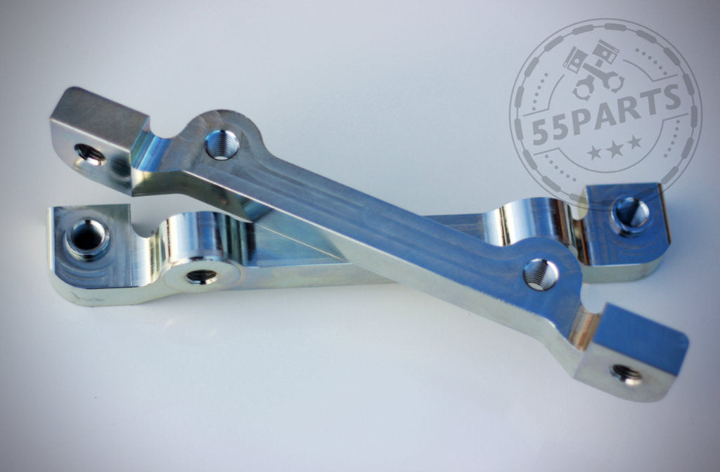 Zwei silberne 55Parts Bremssatteladapter passend für BMW 1er E8x sitzen überlappend auf einer weißen Fläche, ausgelegt für M3 E46 CSL Scheibe; 6-Kolben, zweiteilig. 55Parts-Logo in der Ecke sichtbar.