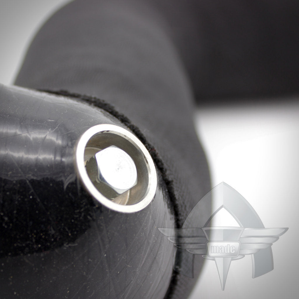 Nahaufnahme eines schwarzen Metallobjekts mit einer Schraube, teilweise von einer schwarzen Stoffhülle bedeckt und mit einem Logo versehen, kompatibel mit dem 55Parts Exclusive ATmade Custom Silicone Hose Kit Ladeluftverrohrung von ATmade.