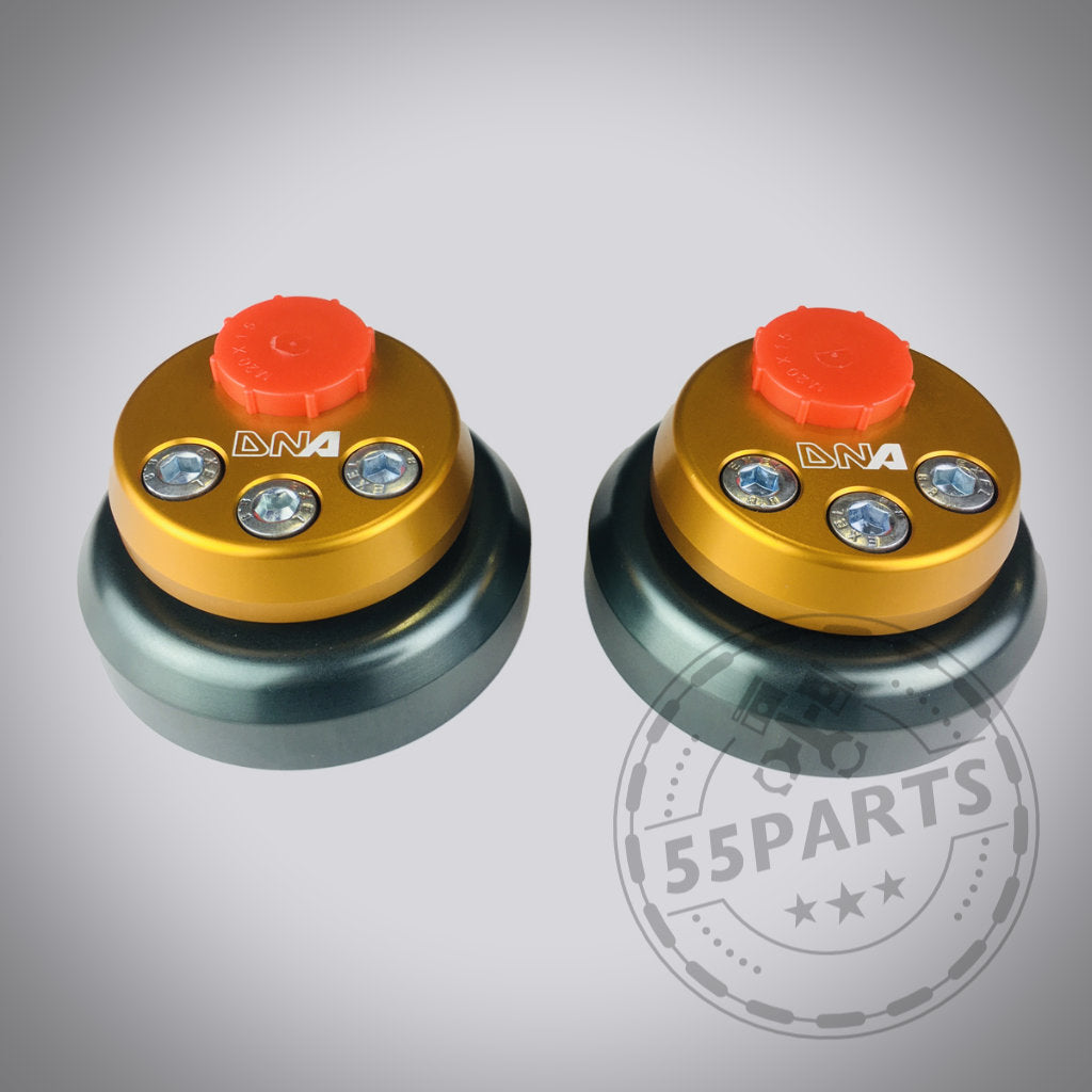 Werten Sie Ihren Toyota Yaris GR mit den verstellbaren Uniball Domlagern von DNA Racing auf – runde Halterungen in Gold und Schwarz mit roten Knöpfen, silbernen Schrauben und einem DNA Racing-Logo – ideal für Upgrades im Tuning-Shop.