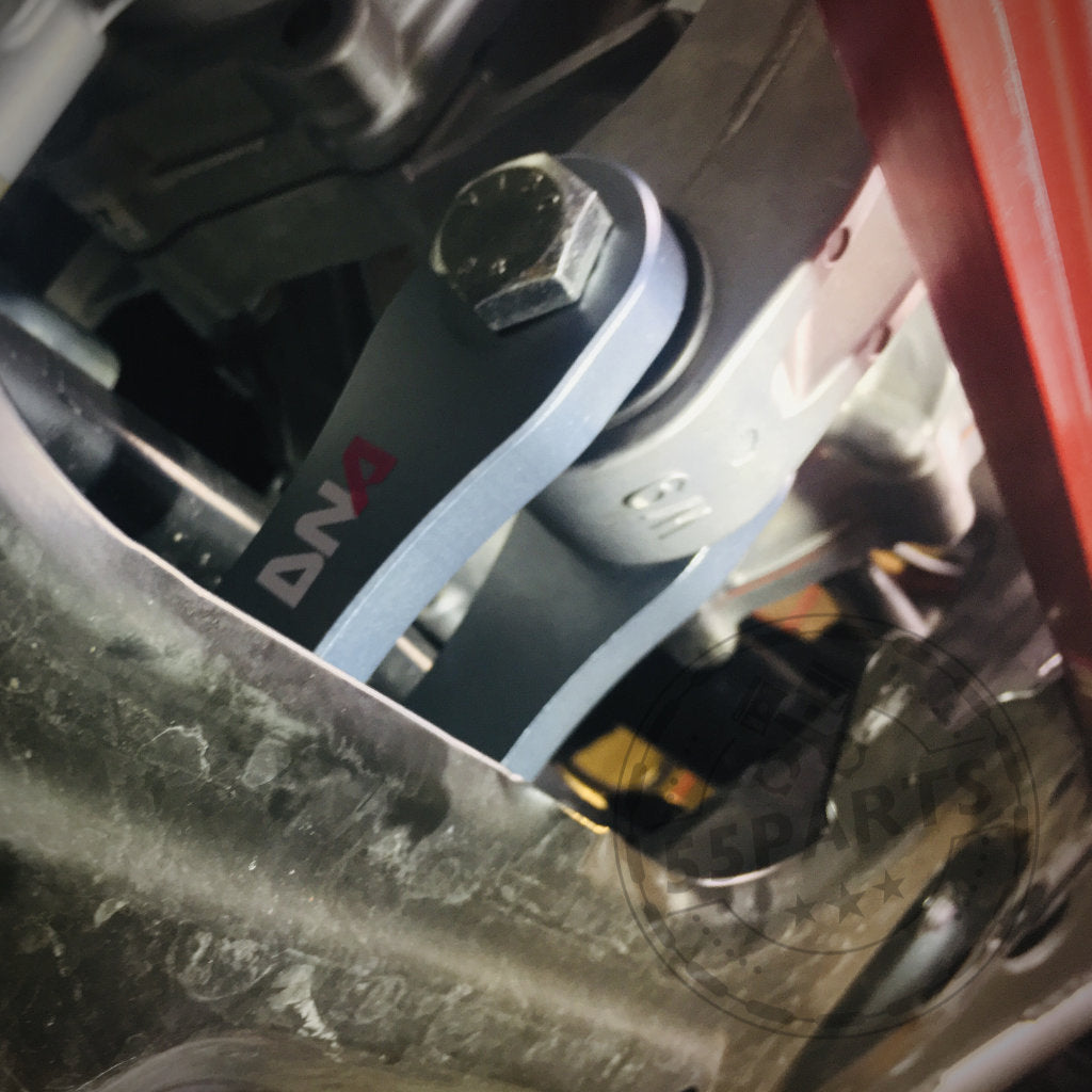 Nahaufnahme des für den Toyota Yaris GR entwickelten DNA Racing Upgrade Drehmoment Stütze-Motorlagers, das neben anderen mechanischen Teilen gezeigt wird, um die Fahrwerk-Funktionen hervorzuheben.