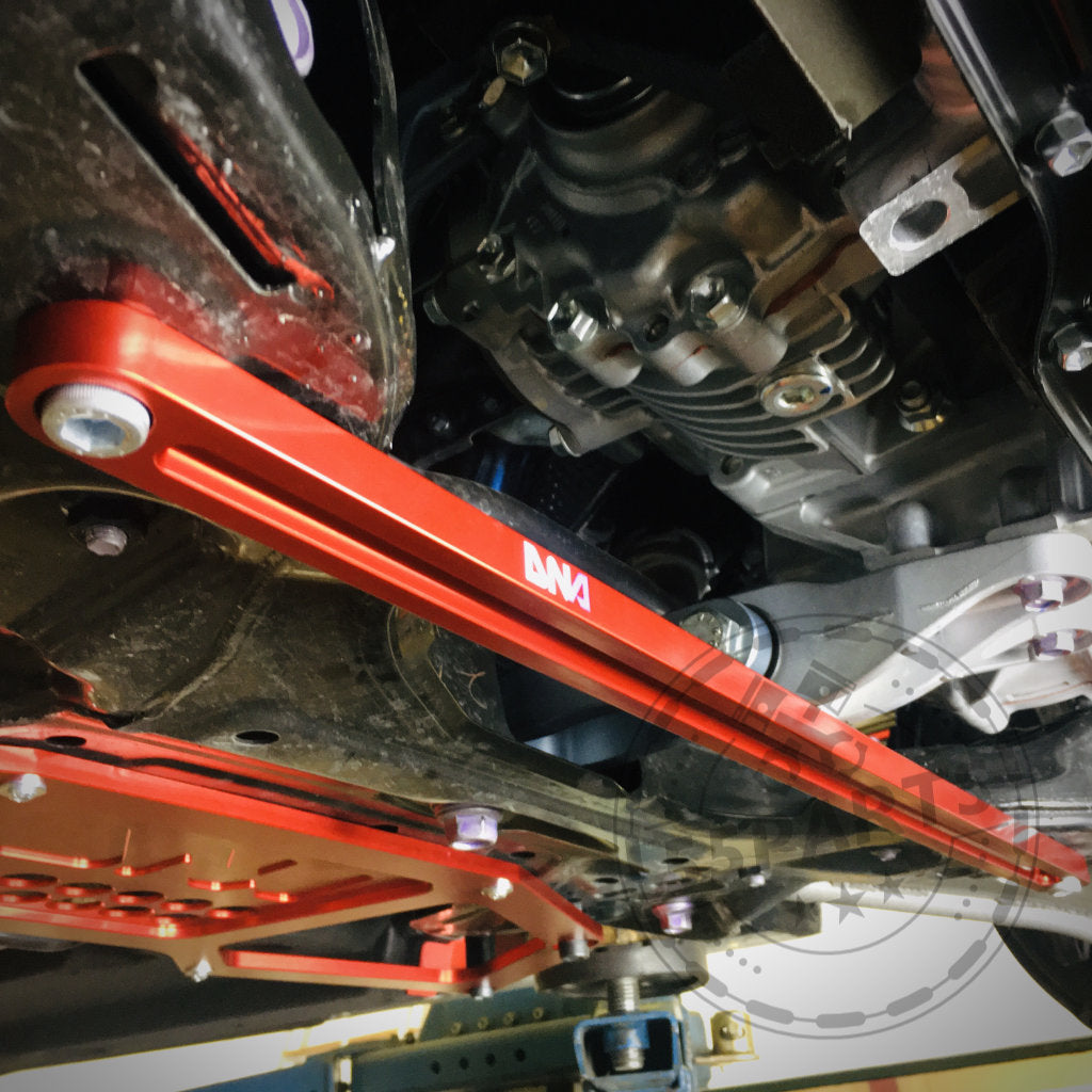 Die Unterseite eines Yaris GR zeigt einen roten DNA Racing Versteifungsstrebe vorderer Achsträger vorne, der für präzise Abstimmung und perfekte Passform bei Toyota Yaris GR-Modellen entwickelt wurde.