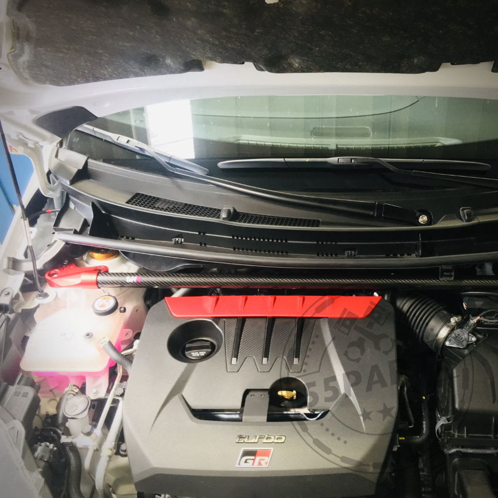 Blick auf den Motorraum eines Yaris GR mit der DNA Racing Carbon Domstrebe vorne von DNA Racing – ein ideales Upgrade für Toyota Yaris GR-Fans, die Inspiration für ihre Tuning-Werkstatt suchen.