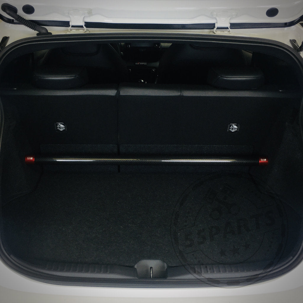 Der geöffnete Kofferraum des Yaris GR gibt den Blick auf einen geräumigen, mit Teppich ausgelegten Laderaum frei, wenn die Rücksitze umgeklappt sind und die DNA Racing Carbon-Domstrebe hinten angebracht ist – ideal für Fahrspaß oder Ihren nächsten Besuch im Tuning-Shop.